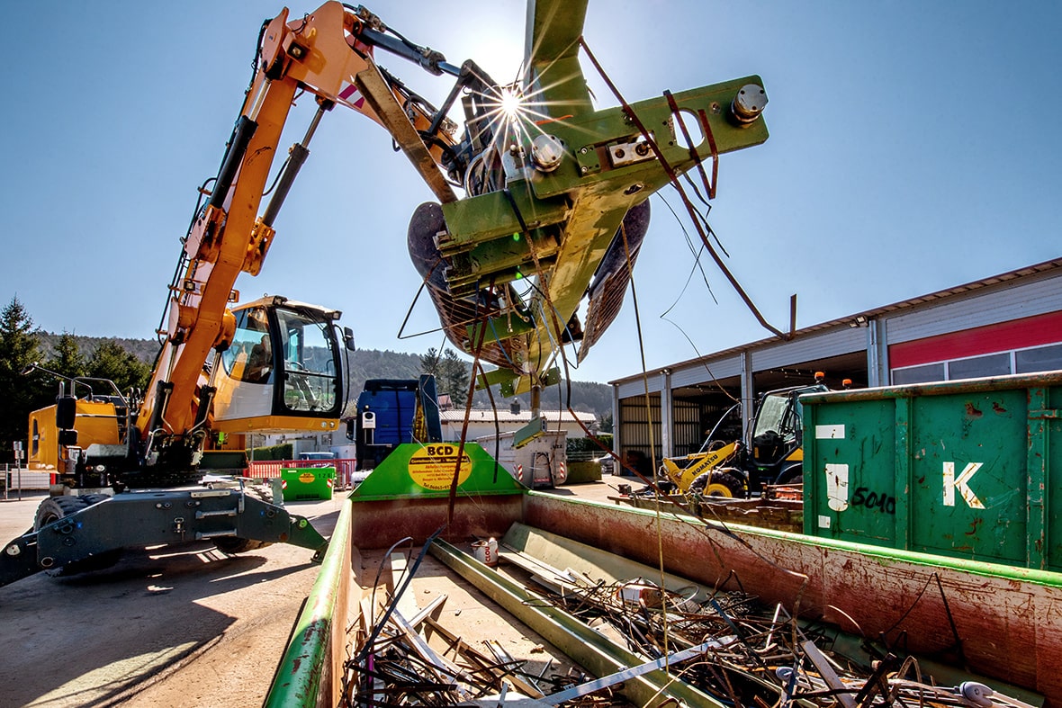 Ein Bagger verlädt Metall-Schrott